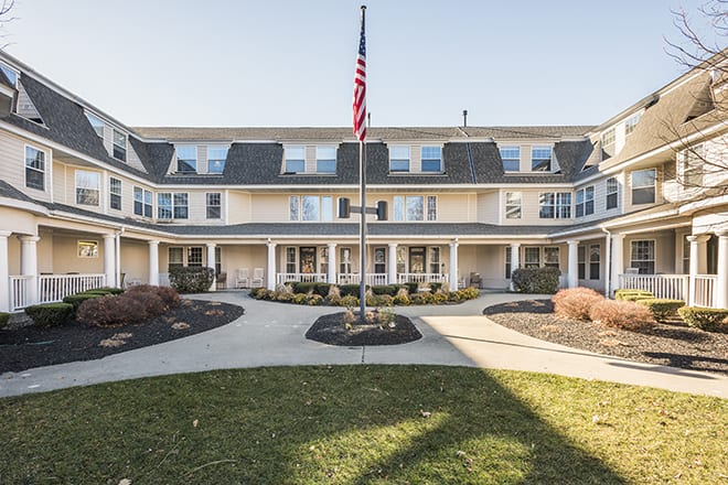 A symmetrical building with a central pathway and an American flag in front.