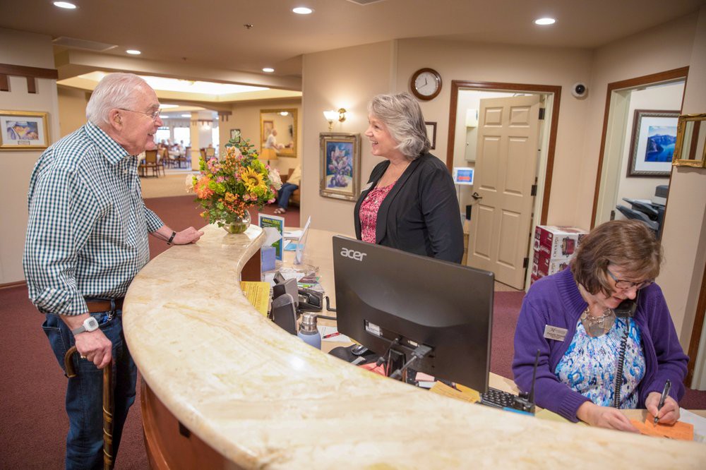 People interacting at a reception desk in a lobby.