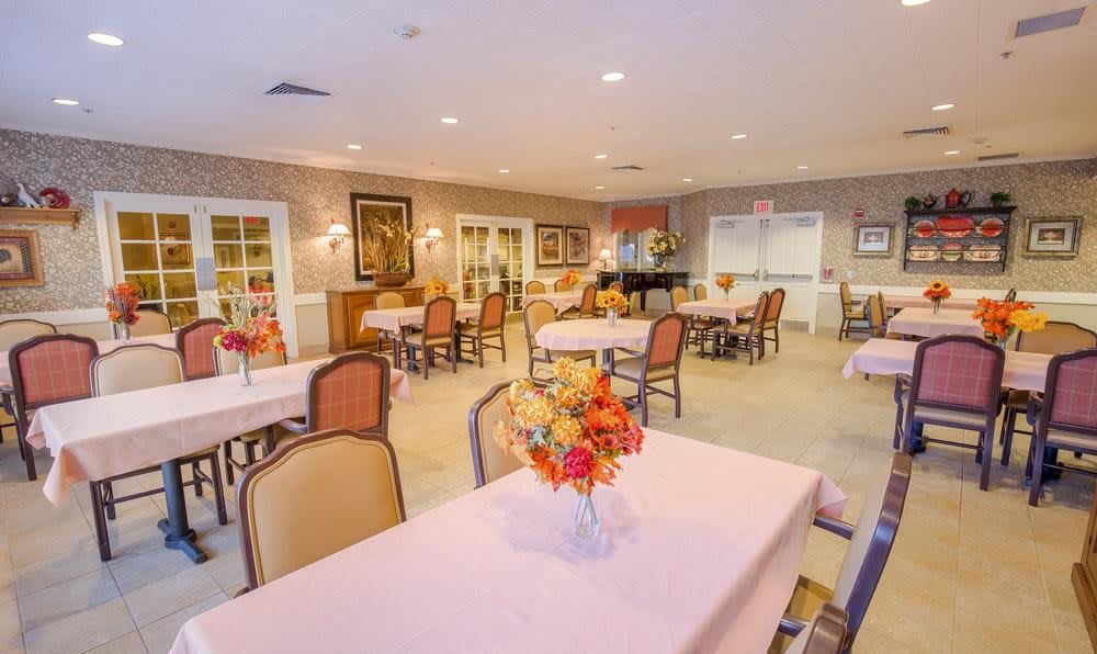 A well-lit dining area with neatly arranged tables and floral centerpieces.