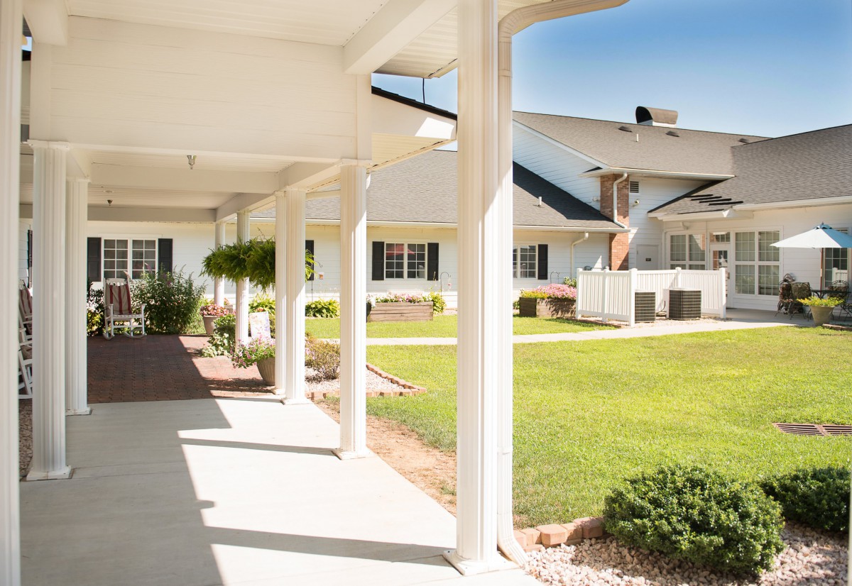 A sunny view of a suburban residential area with a covered porch and well-maintained lawn.