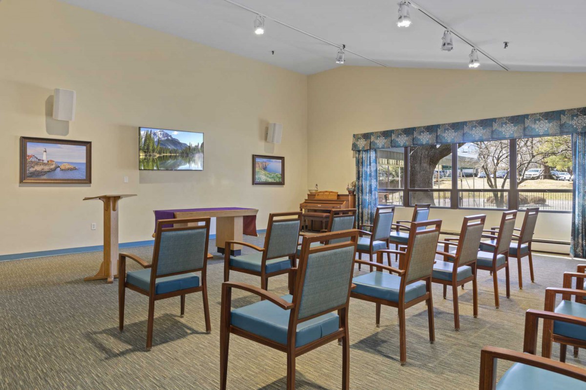 A meeting room setup with chairs arranged in rows, featuring a lectern and a television on the wall.