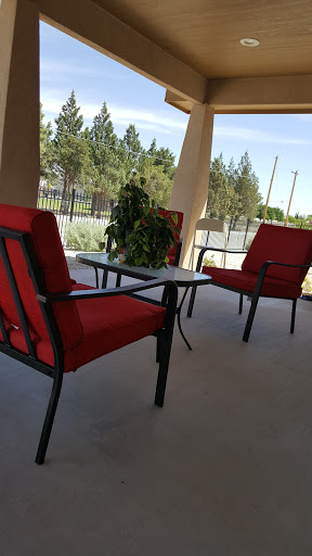 A cozy outdoor seating area with red cushioned chairs and a small table, perfect for relaxation.