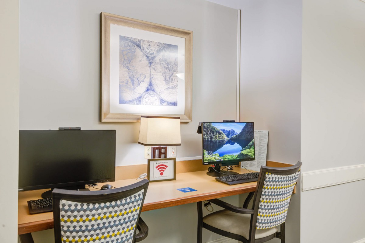 A cozy workstation with dual monitors and a decorative lamp on the desk.