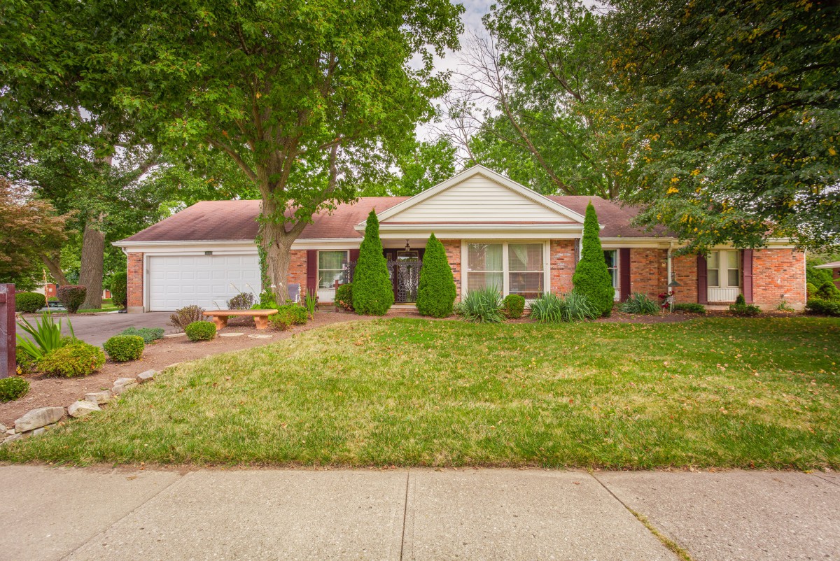 A suburban house with a well-maintained front yard and trees lining the property.