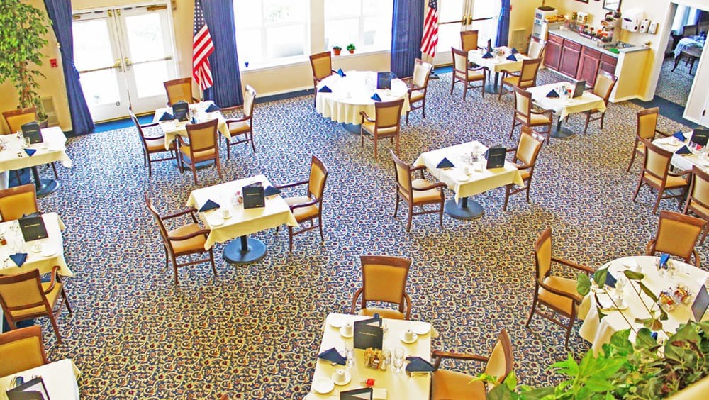 An empty dining area with neatly arranged tables and chairs, featuring prominent flag decorations.