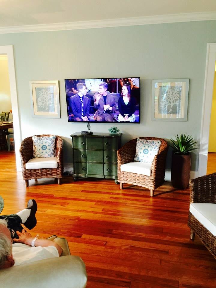 A cozy living room with a mounted television and wicker furniture.