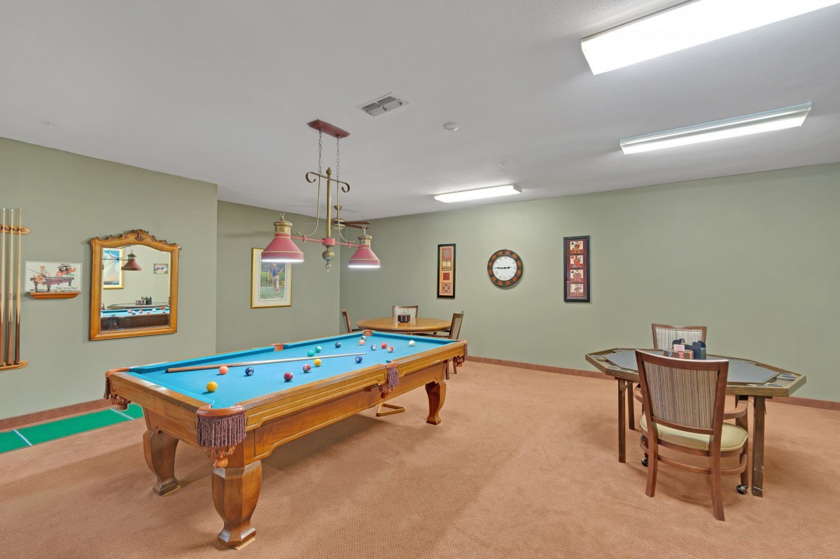 A well-lit game room featuring a pool table and seating area.