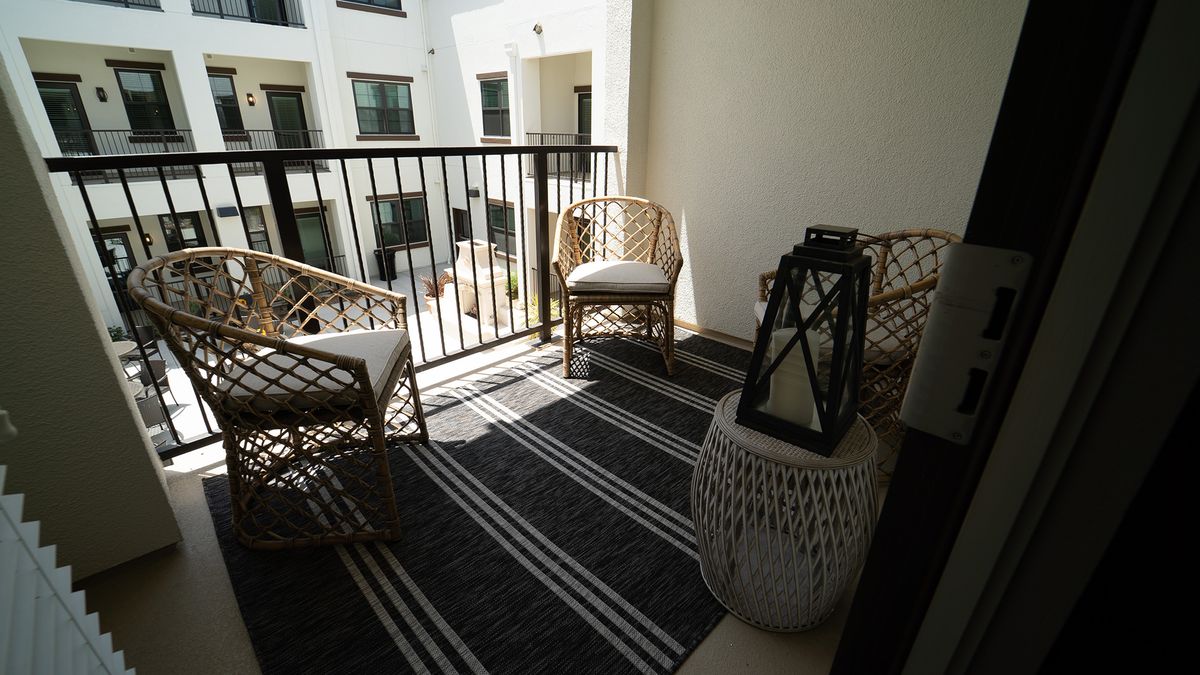A cozy balcony with rattan chairs and a decorative lantern, perfect for relaxing.