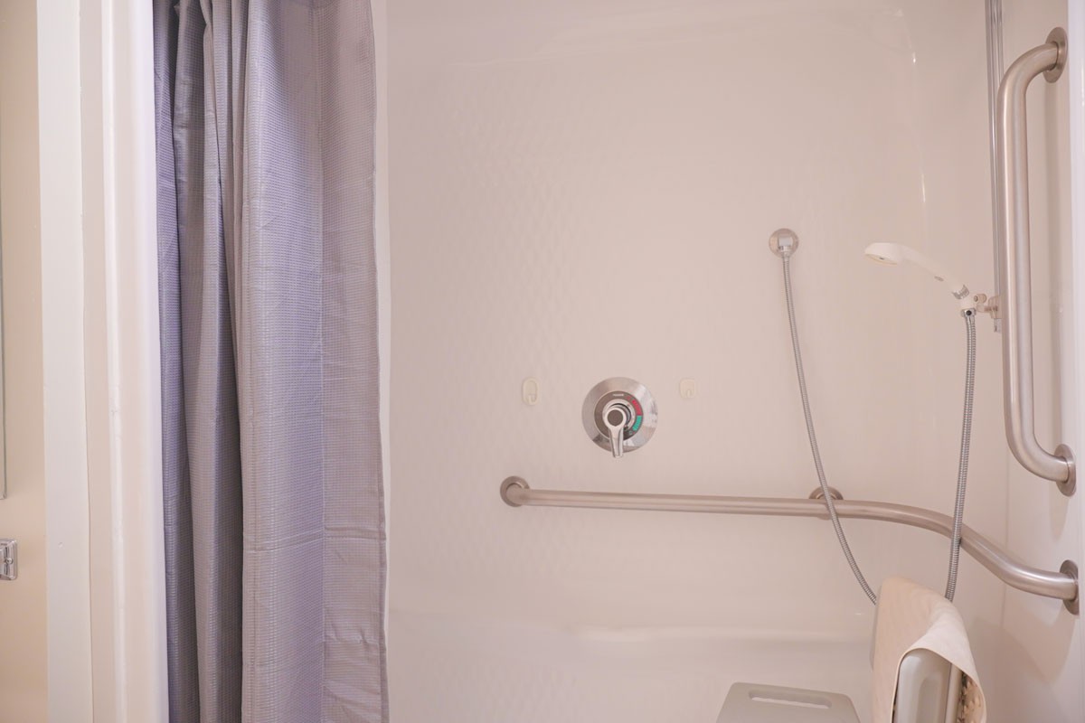 A bathroom shower with a curtain and grab bar.