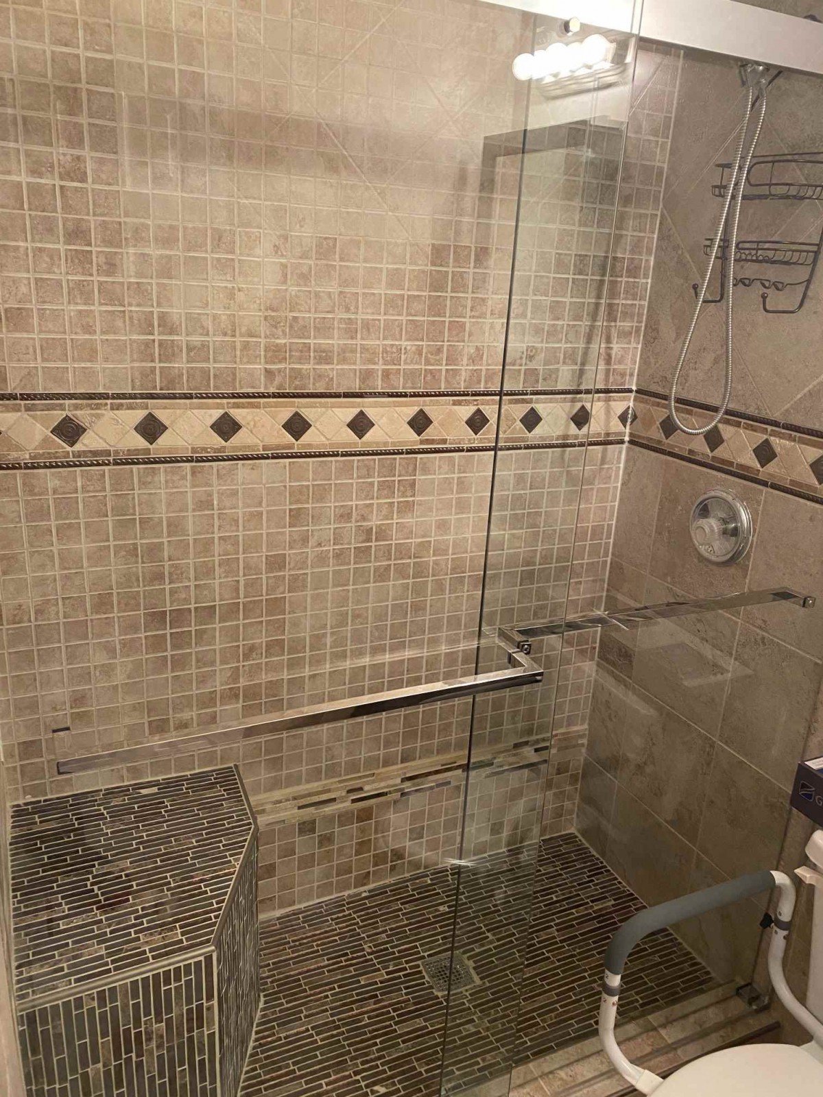 A modern shower with glass doors and decorative tile work.