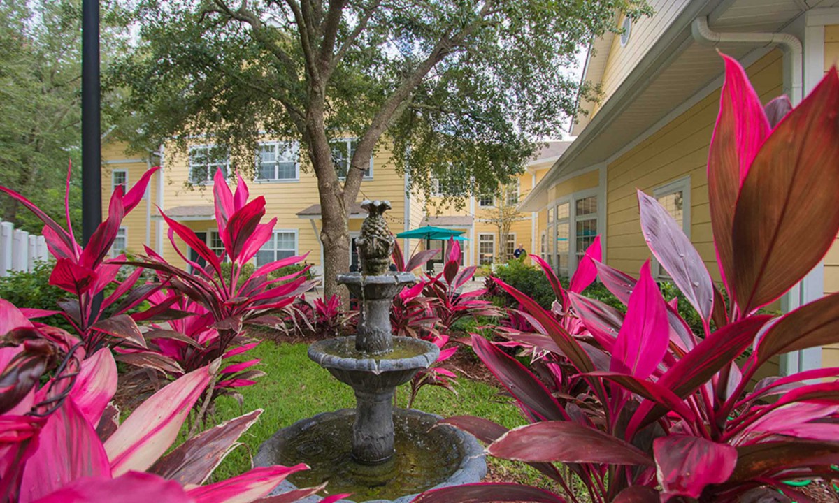 A serene courtyard garden featuring a central fountain surrounded by vibrant red foliage.