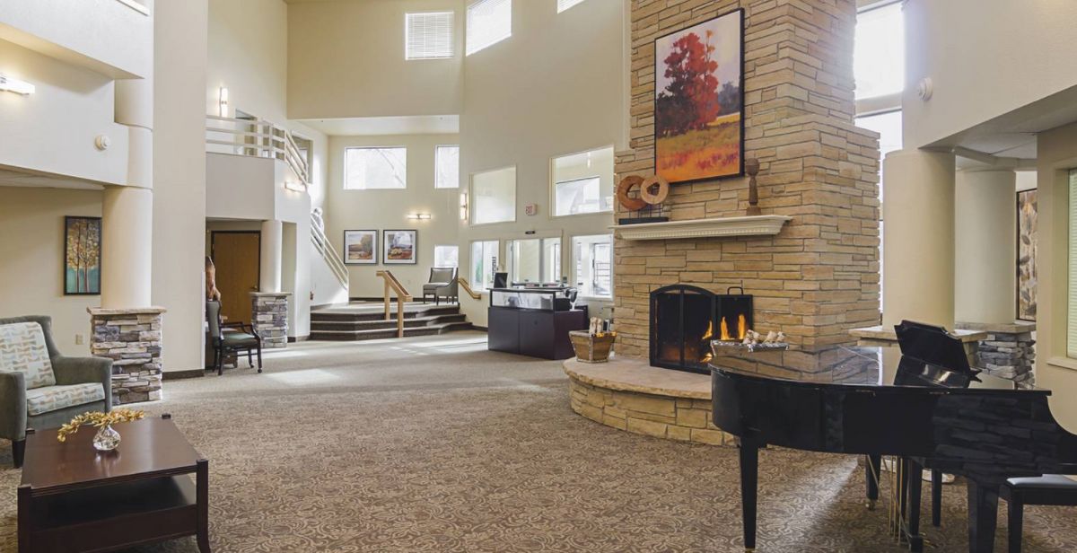A spacious living room with a fireplace and grand piano, showcasing contemporary interior design.