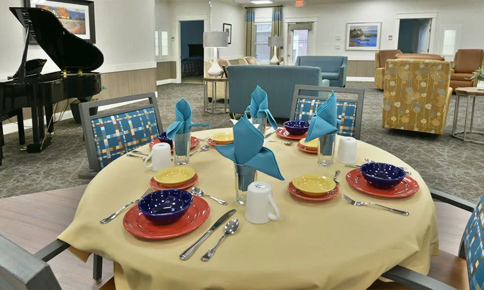 A neatly arranged dining table with colorful plates and decorative napkins in an inviting indoor setting.