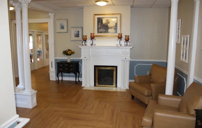 A cozy living room with a fireplace, decorated with artwork and classic furniture.