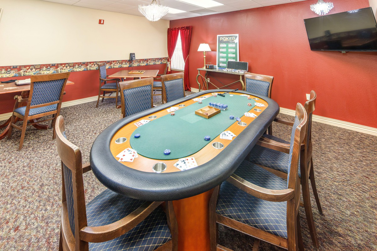 A cozy gaming room featuring a poker table with chairs and card games set up.