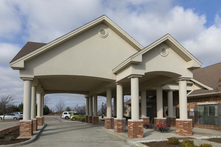 A building entrance with a covered driveway and columns.