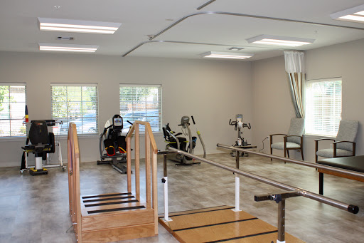 A well-equipped physical therapy room featuring various exercise machines and a wooden ramp for rehabilitation.