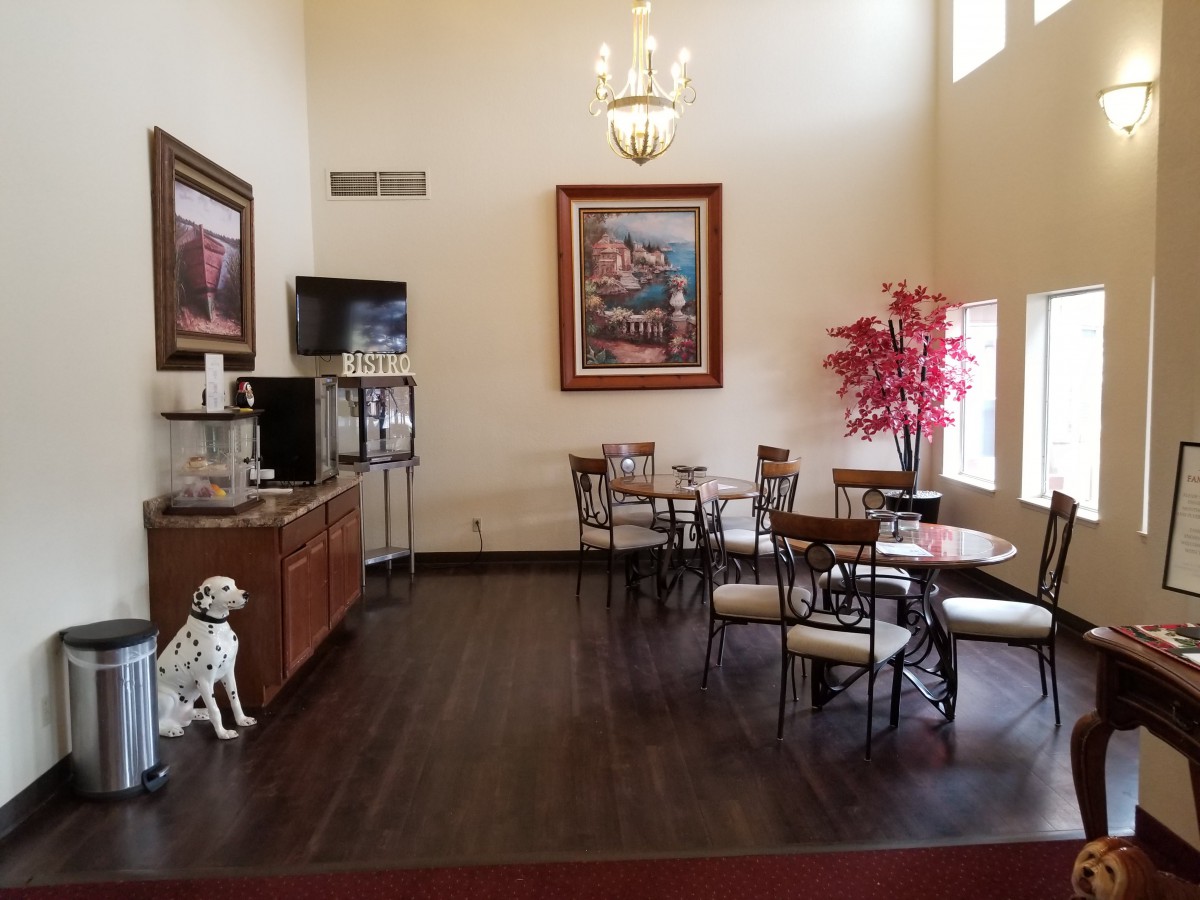 A cozy hotel lobby cafe area with seating, a coffee station, and decorative elements.