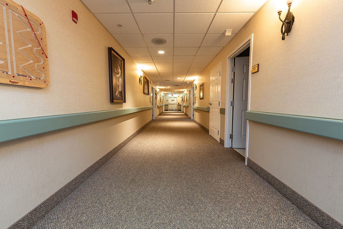 A long, well-lit hallway with carpeted floors and doors along the sides.