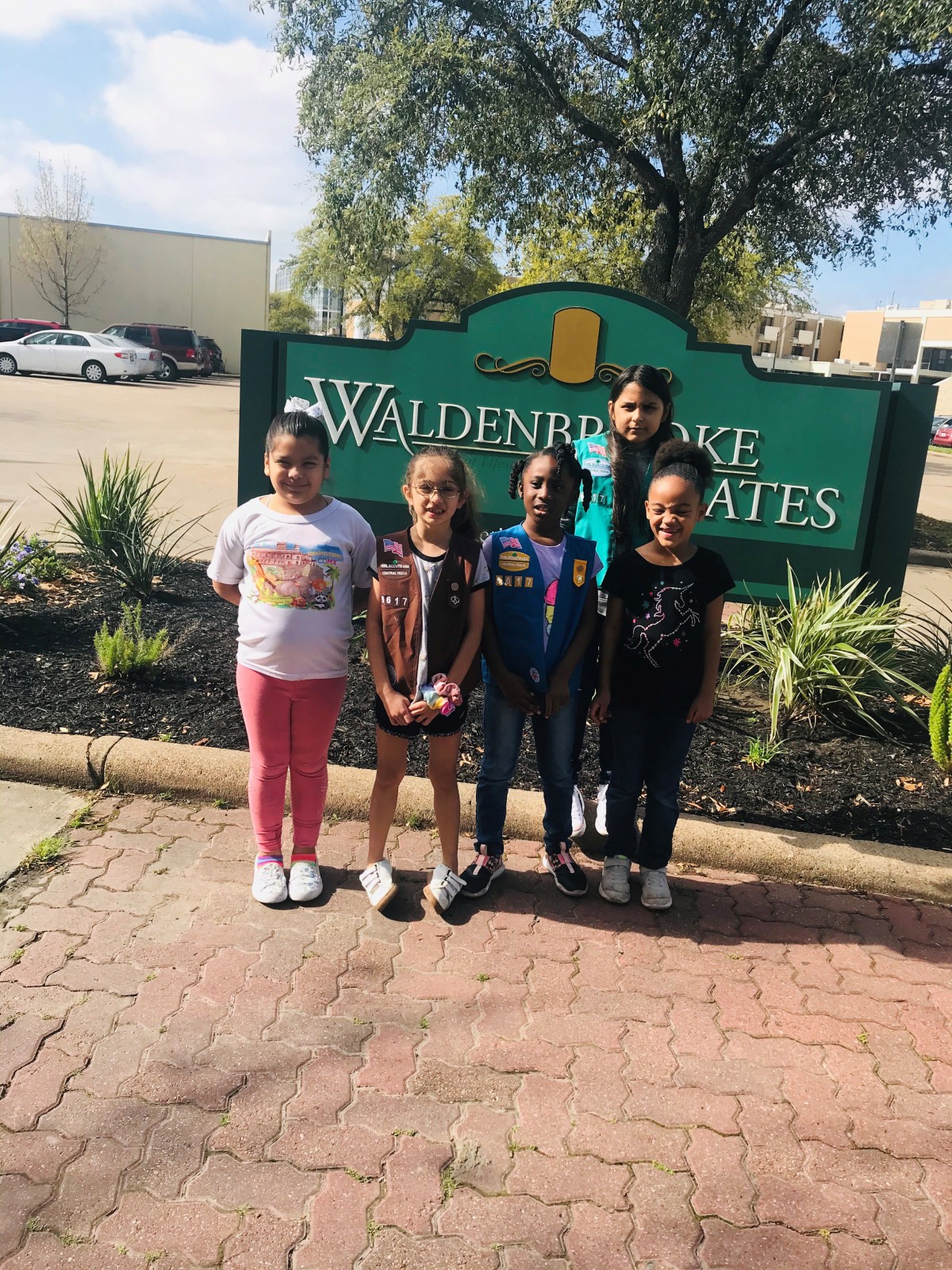 A group of children standing in front of a sign outdoors.