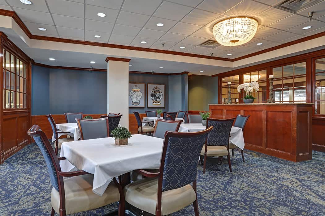 A well-appointed restaurant dining area with tables, chairs, and a chandelier.