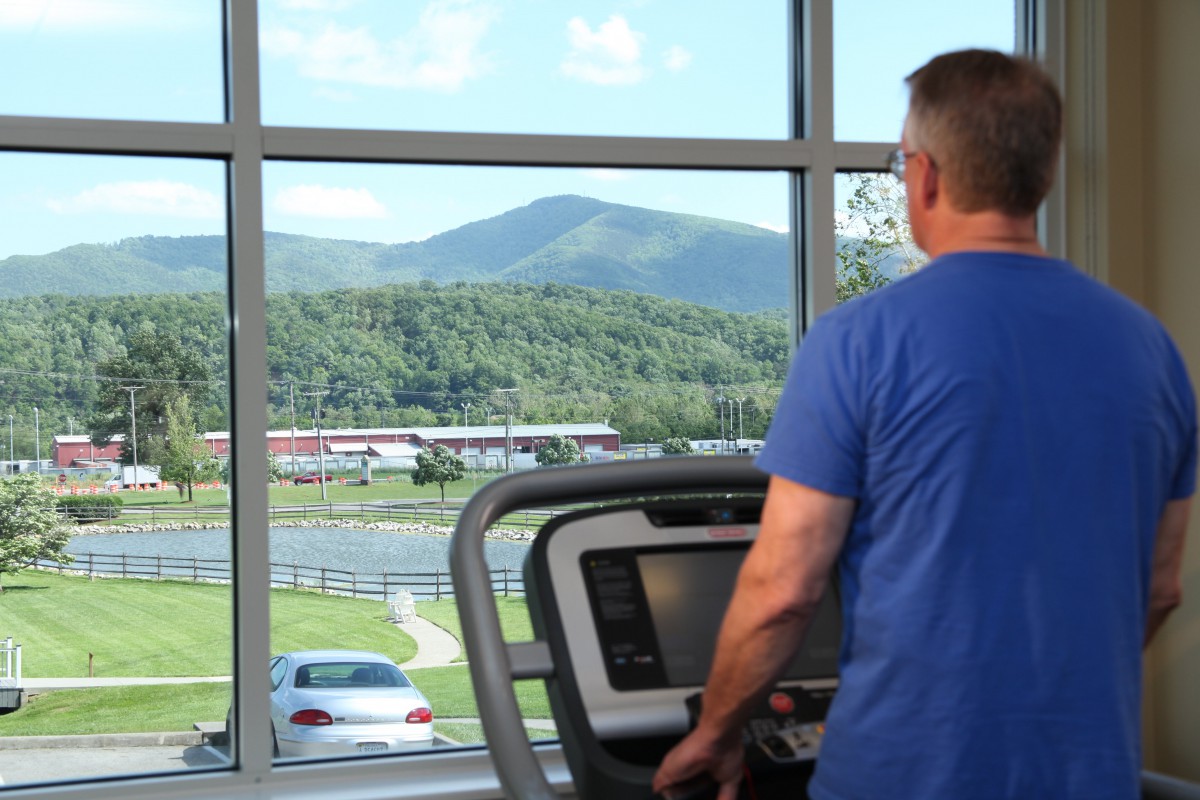 A person exercising on a treadmill with a scenic mountain view in the background.