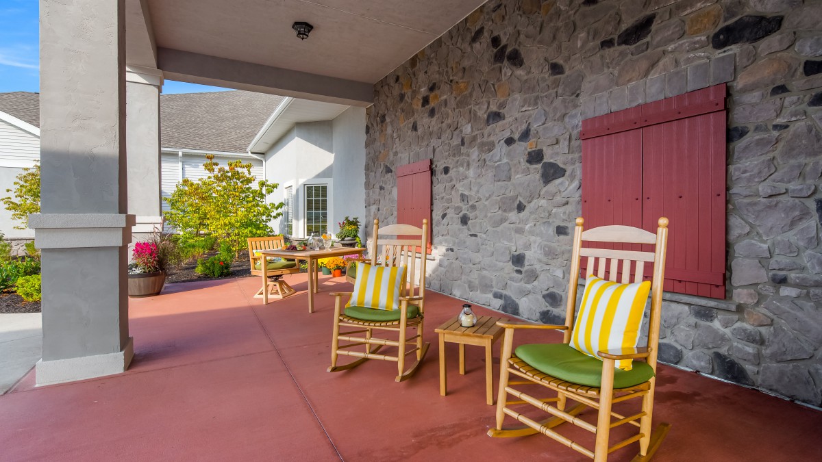A cozy patio with wooden rocking chairs and a stone wall backdrop.