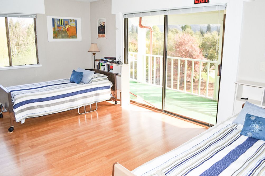 A bright and airy bedroom with two beds and a balcony view.