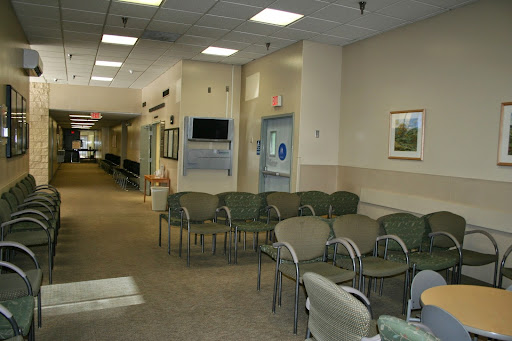 A quiet waiting room in a medical facility, featuring several chairs and a corridor leading to other areas.