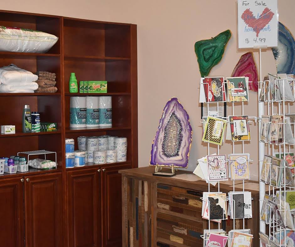 A cozy store interior featuring shelves stocked with various products, greeting cards, and decorative geodes.