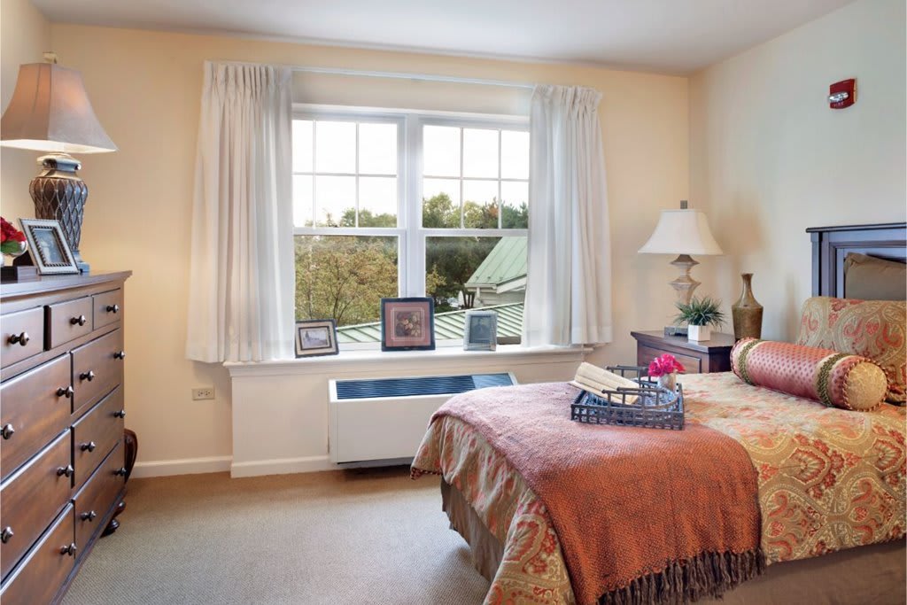 Cozy bedroom featuring a large window with curtains, a bed, and decorative elements.