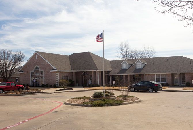 A one-story building with a flagpole and car in the parking lot.