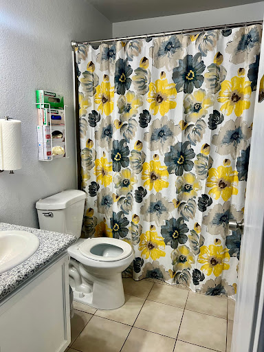 A bright and cheerful bathroom featuring a floral shower curtain, modern toilet, and sink.