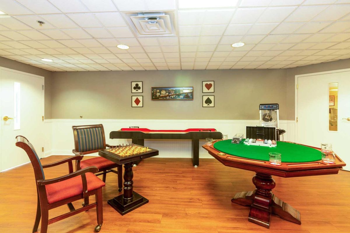 A cozy game room featuring a poker table, shuffleboard, and a popcorn machine.