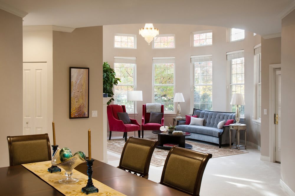 A stylish living and dining area with ample natural light flooding through large windows, featuring cozy seating and elegant decor.