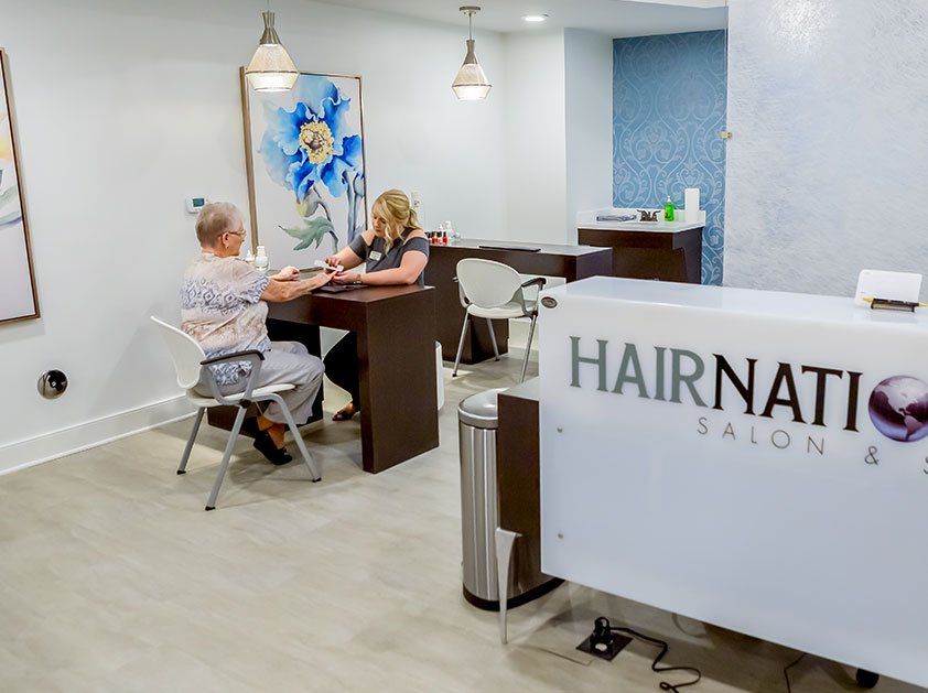 A modern reception area with a desk and two people interacting, featuring stylish decor and furniture.
