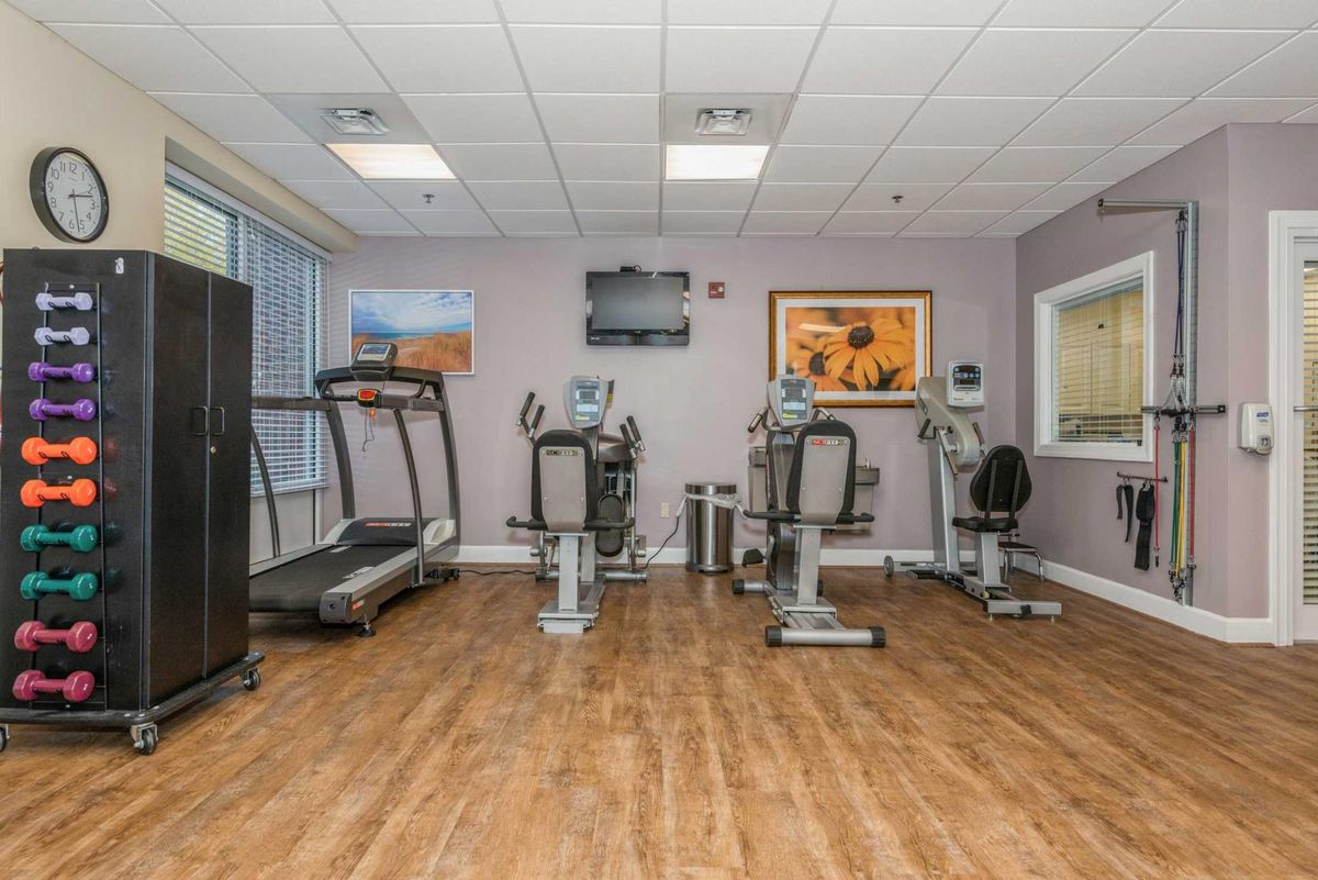 A well-equipped gym room featuring a treadmill and stationary bikes.