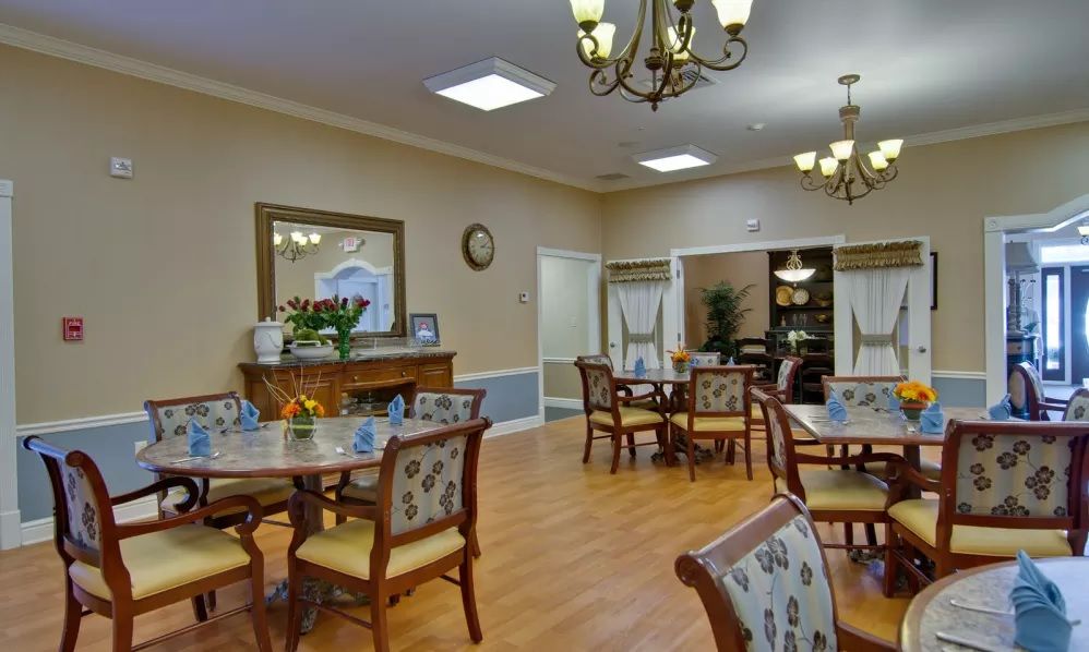 A well-decorated dining room with floral upholstered chairs and elegant chandeliers.
