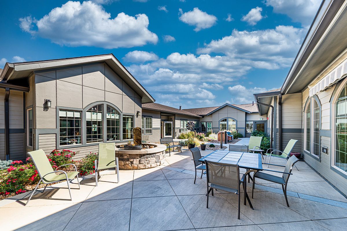 A spacious patio with outdoor furniture set against a backdrop of a house and a clear blue sky.