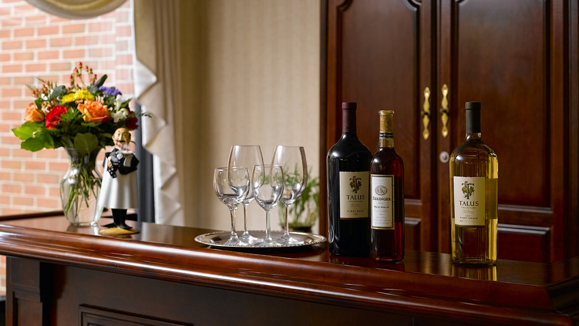 A luxurious bar setup featuring wine bottles and glasses on a polished wooden counter.
