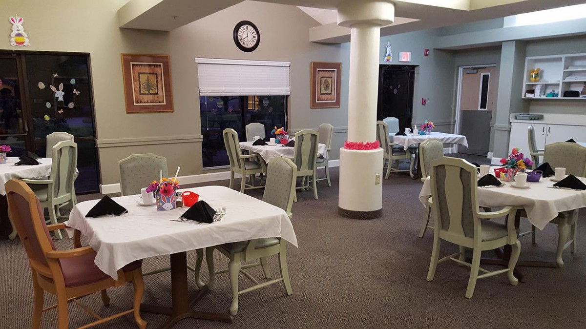 A cozy dining room with decorated tables, elegant chairs, and framed art on the walls.