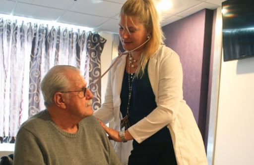 A healthcare professional using a stethoscope to examine an elderly patient.
