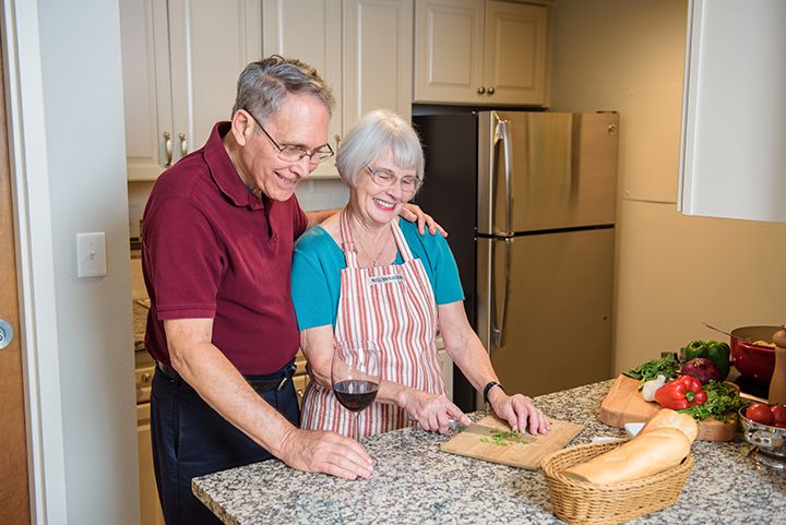 An elderly couple enjoying cooking together in the kitchen.