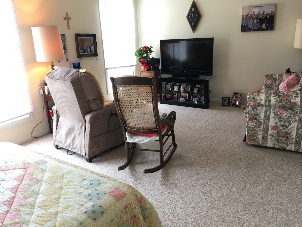 A cozy living room with a rocking chair and a television.