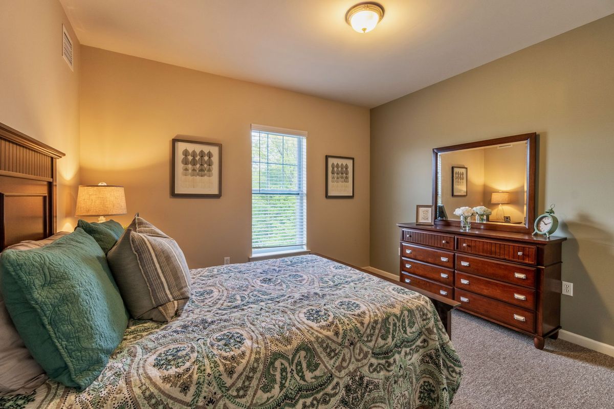 A cozy bedroom with a bed, dresser, and decorative elements.