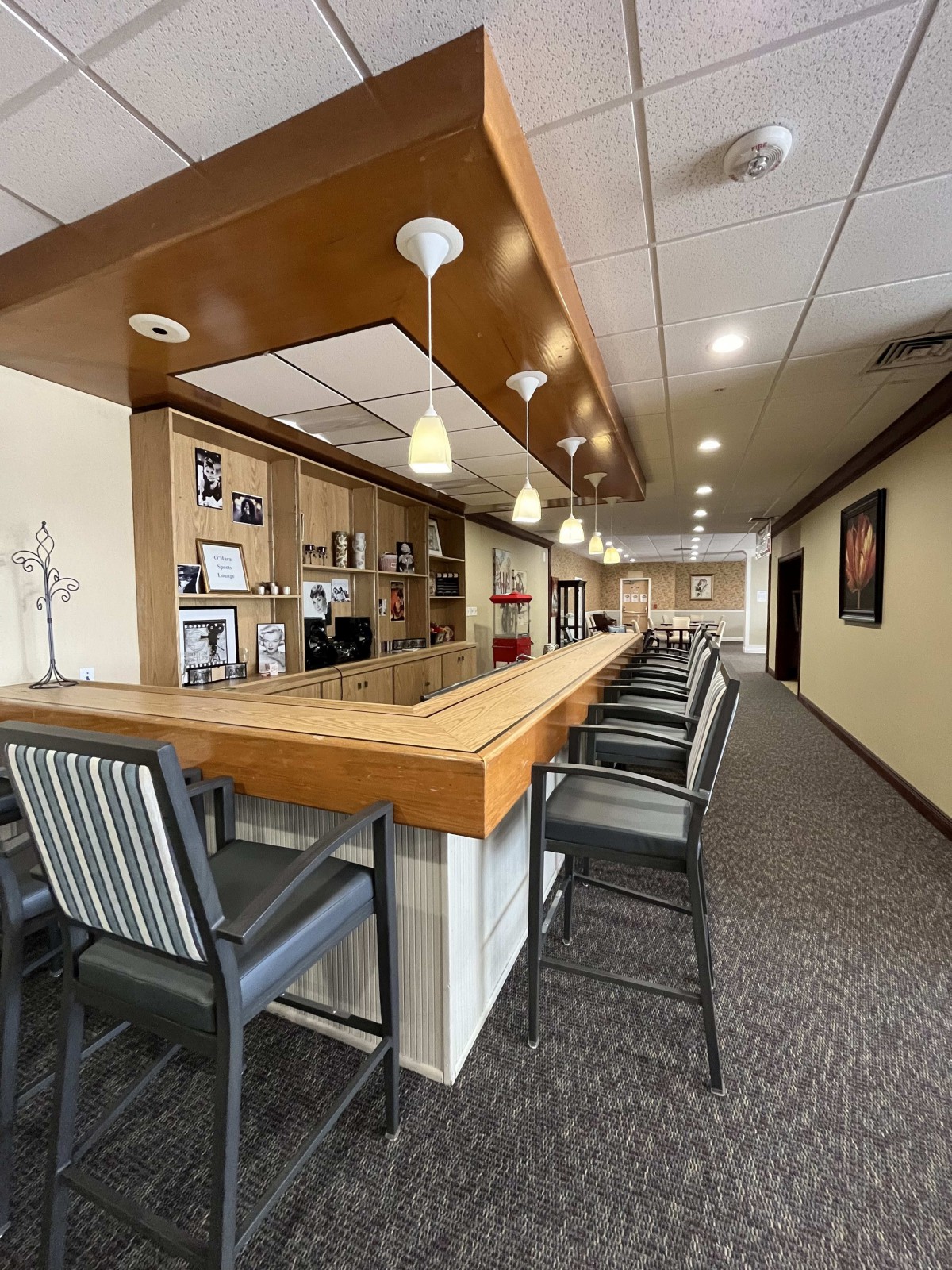 A modern bar area with high chairs, wooden countertop, and ambient lighting.