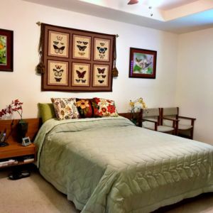 A cozy bedroom featuring a neatly made bed with decorative pillows, wall art, and warm lighting.
