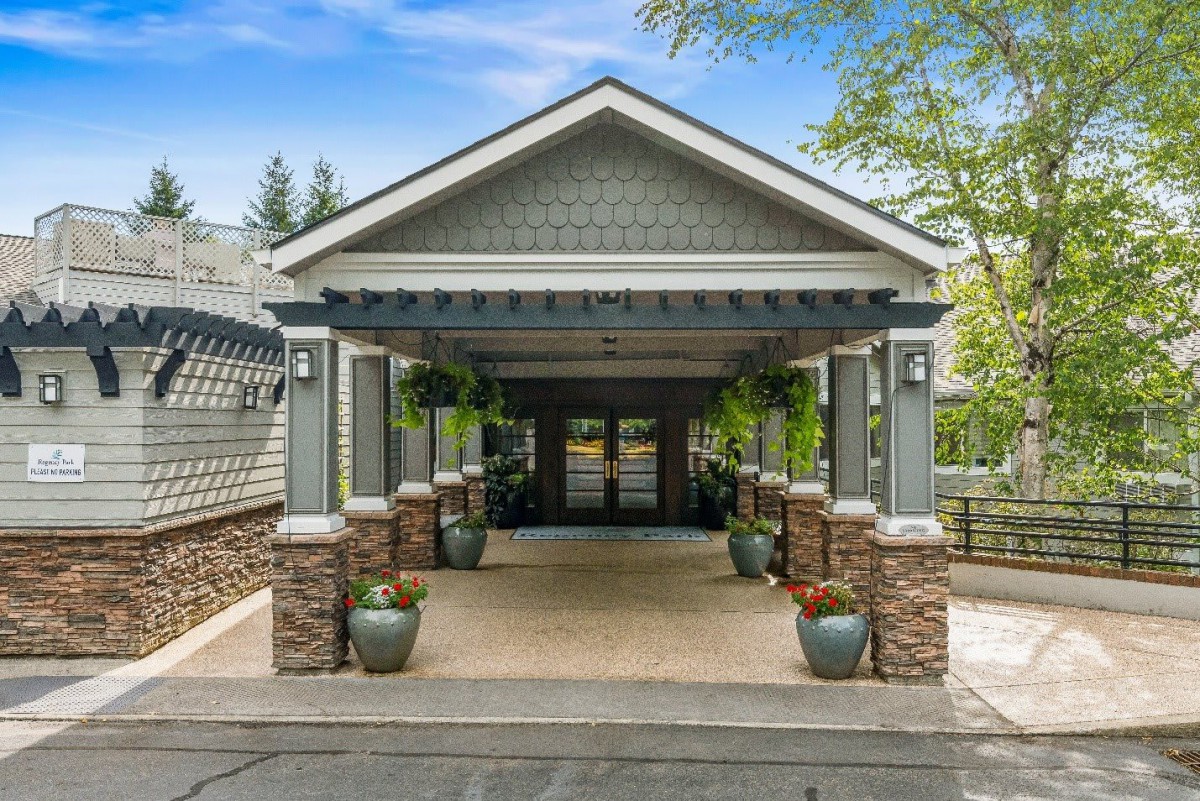 A well-maintained building entrance with a covered walkway and decorative potted plants.