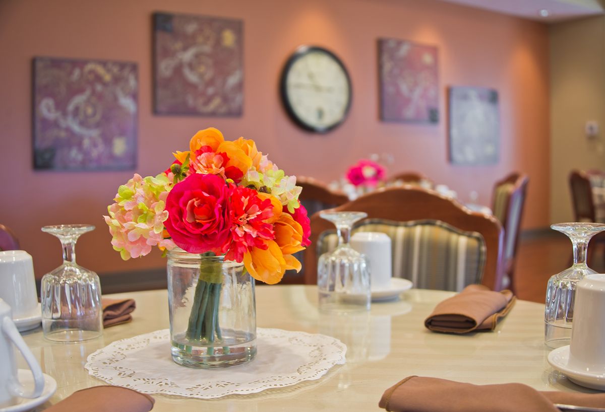 A beautifully set dining table with a vibrant flower centerpiece in a cozy restaurant setting.