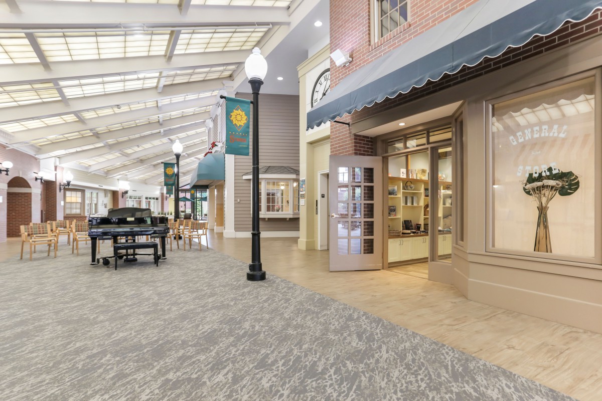 A well-lit indoor shopping area with decorative street lamps and storefronts under a glass ceiling.